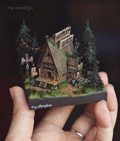 someone is holding up a miniature house made out of wood and paper with the words mystery shack on it