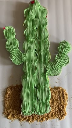 a cake shaped like a cactus sitting on top of a white sheet covered in green frosting