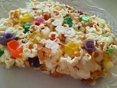 a white plate topped with popcorn covered in gummy bears and candy bars on top of it