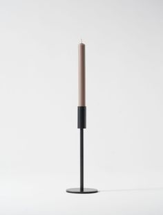 a single candle sitting on top of a black stand