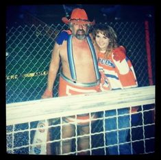 a man and woman standing next to each other in front of a fence