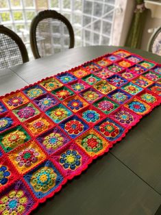 a crocheted table runner on top of a dining room table with chairs in the background