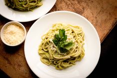 two plates of pasta with parsley and parsley on top, next to a small bowl of parsley