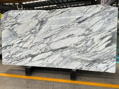 a large white marble slab sitting on top of a metal stand in a warehouse with yellow lines