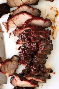 sliced meat on a cutting board next to a knife