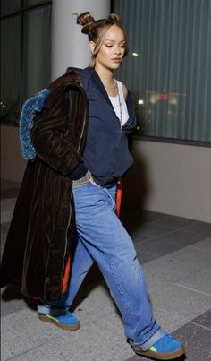 a woman is walking down the street wearing blue jeans