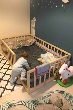 a little boy that is laying in a crib next to a wall with stars on it