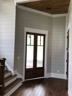 an empty room with wooden floors and two doors leading to the second floor, which has been painted white