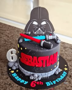 a star wars birthday cake with darth vader and 6th birthday candles on it