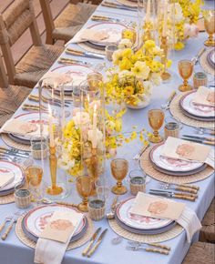 the table is set with yellow flowers and place settings