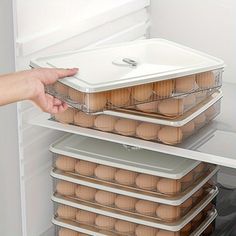 an open refrigerator with eggs in it and someone holding the door to take them out