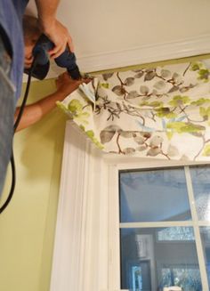 a man is using a power drill to fix a window valance that has been pulled down