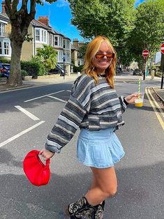 a woman is walking down the street holding a frisbee and a plastic cup