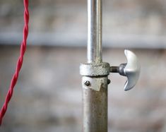 a close up of a metal pole with a red rope attached to it and a wrench on the end