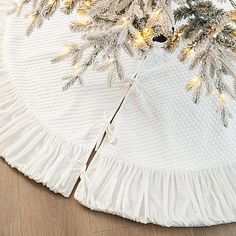 a christmas tree skirt on the floor with pine cones and lights hanging from it's sides