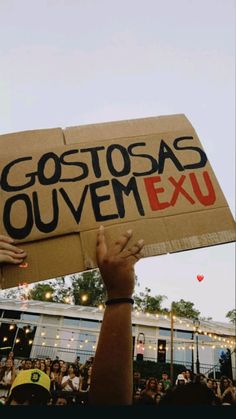 a person holding up a sign that says gostoas quevem exu