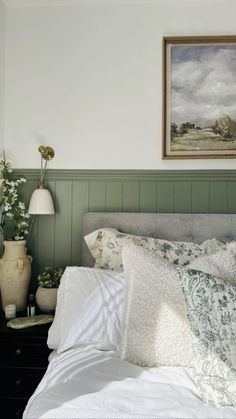 a bedroom with green paneling and white bedding