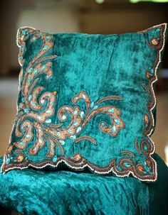 a green velvet chair with a decorative pillow on it