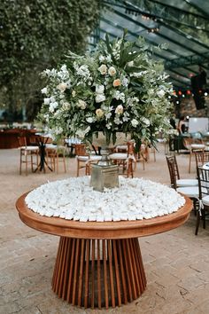 an arrangement of flowers in a vase sitting on top of a table with chairs around it