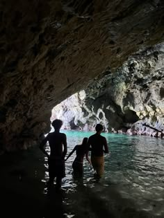 two people are standing in the water near a cave