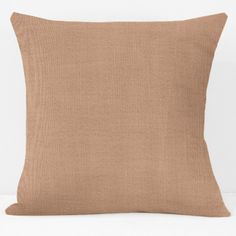 a brown pillow on a white surface with a light colored back ground and the bottom half of it