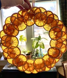 a person holding up an orange glass wreath