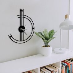 there is a clock on the wall next to a potted plant and bookshelf