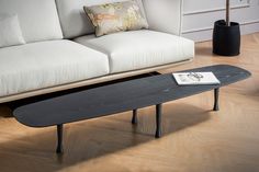 a black skateboard sitting on top of a wooden floor next to a white couch