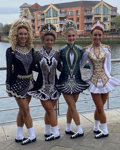 three women in costumes standing next to each other on a bridge over water with buildings in the background