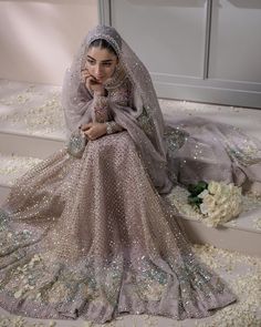 a woman in a wedding dress sitting on some steps with flowers and petals all around her