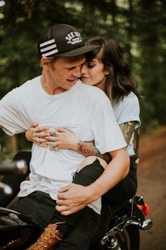 a man and woman are sitting on a motorcycle with their arms wrapped around each other