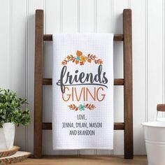 a white towel that says friends giving on it next to a wooden chair and potted plant