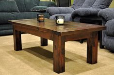 a wooden table sitting on top of a carpeted floor next to two couches