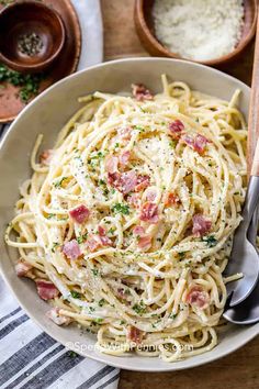 a bowl full of pasta with bacon and parmesan cheese