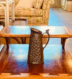 a pitcher sitting on top of a wooden table in a room filled with couches