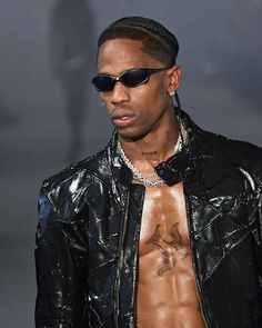 a man with no shirt on walking down the runway wearing sunglasses and a leather jacket