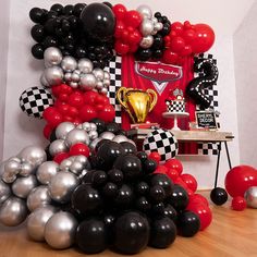 a room filled with balloons and black and silver decorations on the wall, along with a checkered table cloth