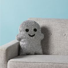 a pillow with a smiley face on it sitting on a couch in front of a blue wall