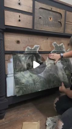 two children are playing with an animal painting on a dresser drawer and the girl is holding her hand out to touch it