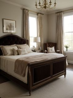 a bedroom with a large bed and chandelier hanging from the ceiling in front of two windows