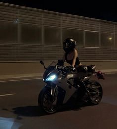 a woman riding on the back of a motorcycle at night