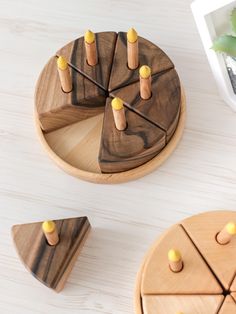 three wooden pieces with pegs on them sitting on a table next to a potted plant