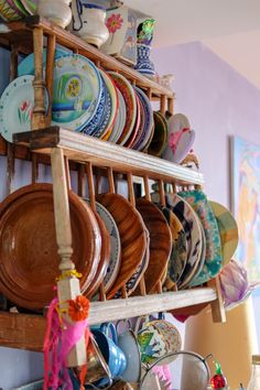 a rack filled with lots of plates on top of a wooden shelf next to a wall