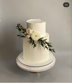 a three tiered white wedding cake with flowers on top