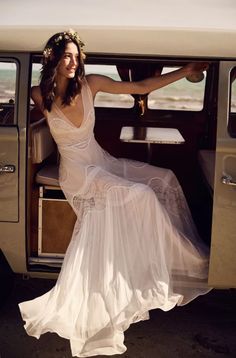 a woman sitting in the back of a white van with her legs crossed and wearing a flower crown