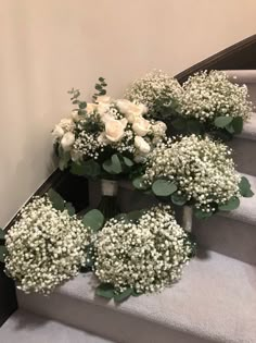 white roses and baby's breath are arranged on the stairs