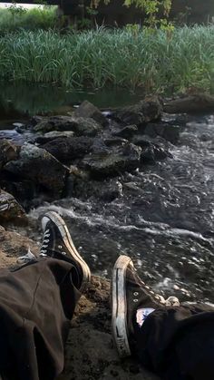 someone's shoes are sitting on the edge of a river