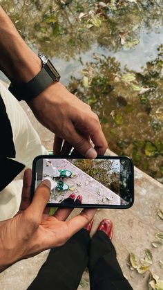 a person holding a cell phone in their hand and looking at the screen with both hands