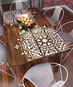 a wooden table with chairs around it and fruit on the table in front of it