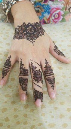 a woman's hand with henna tattoos on it and flowers around the wrist